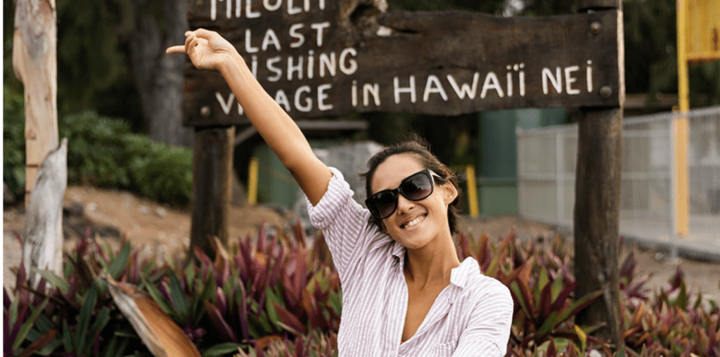 Bad Ass Coffee of Hawaii franchise young woman smiles in front of Hawaii sign