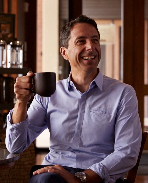 Bad Ass Coffee beverage franchisee new board of director John Coletta smiles with a mug in his hand